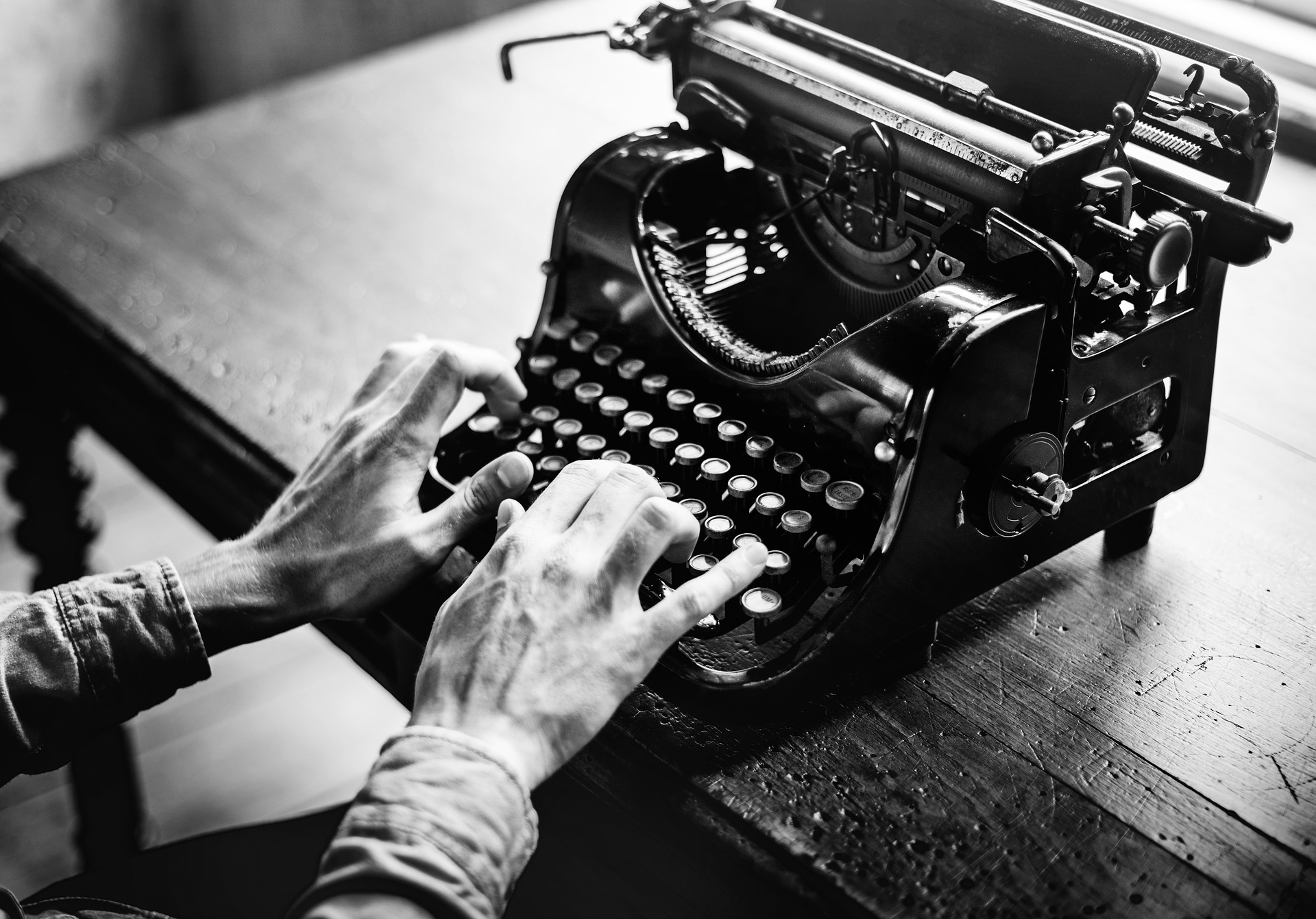 Black and white picture of hands typing on a typewriter